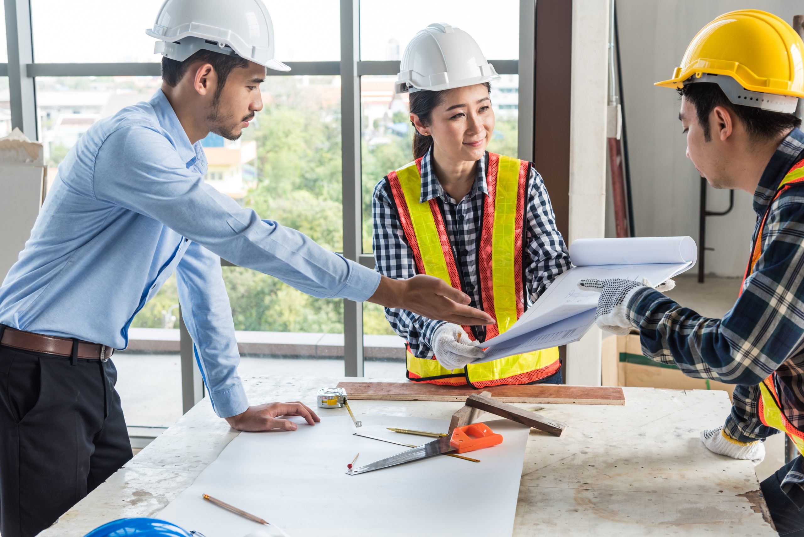 engineering and construction managers discussing project blue print on the table at construction site
